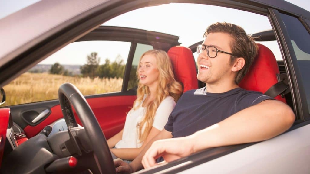 A couple smiling and going somewhere in a car.