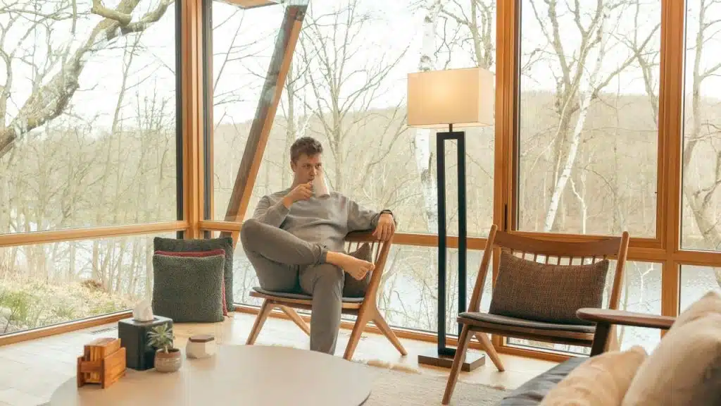 A man drinking from a mug indoors, enjoying the view.