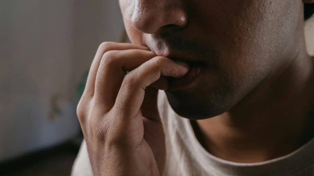 A close-up of someone biting their fingernail.
