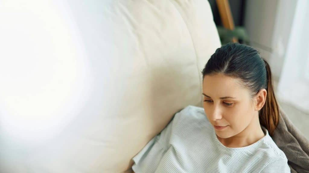 A woman relaxing on a couch, looking down thoughtfully.