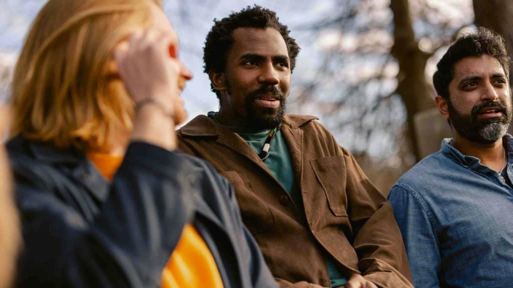 A group of three people talking together outdoors.