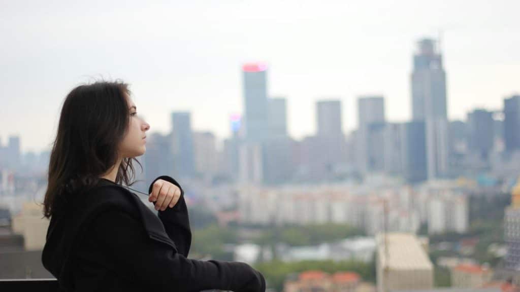 A person in profile looking out over a distant city skyline.