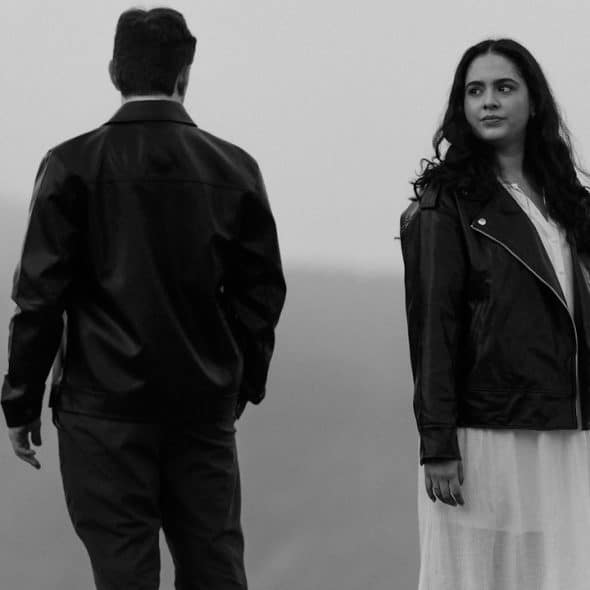A couple standing with their backs to each other and looking in opposite directions.
