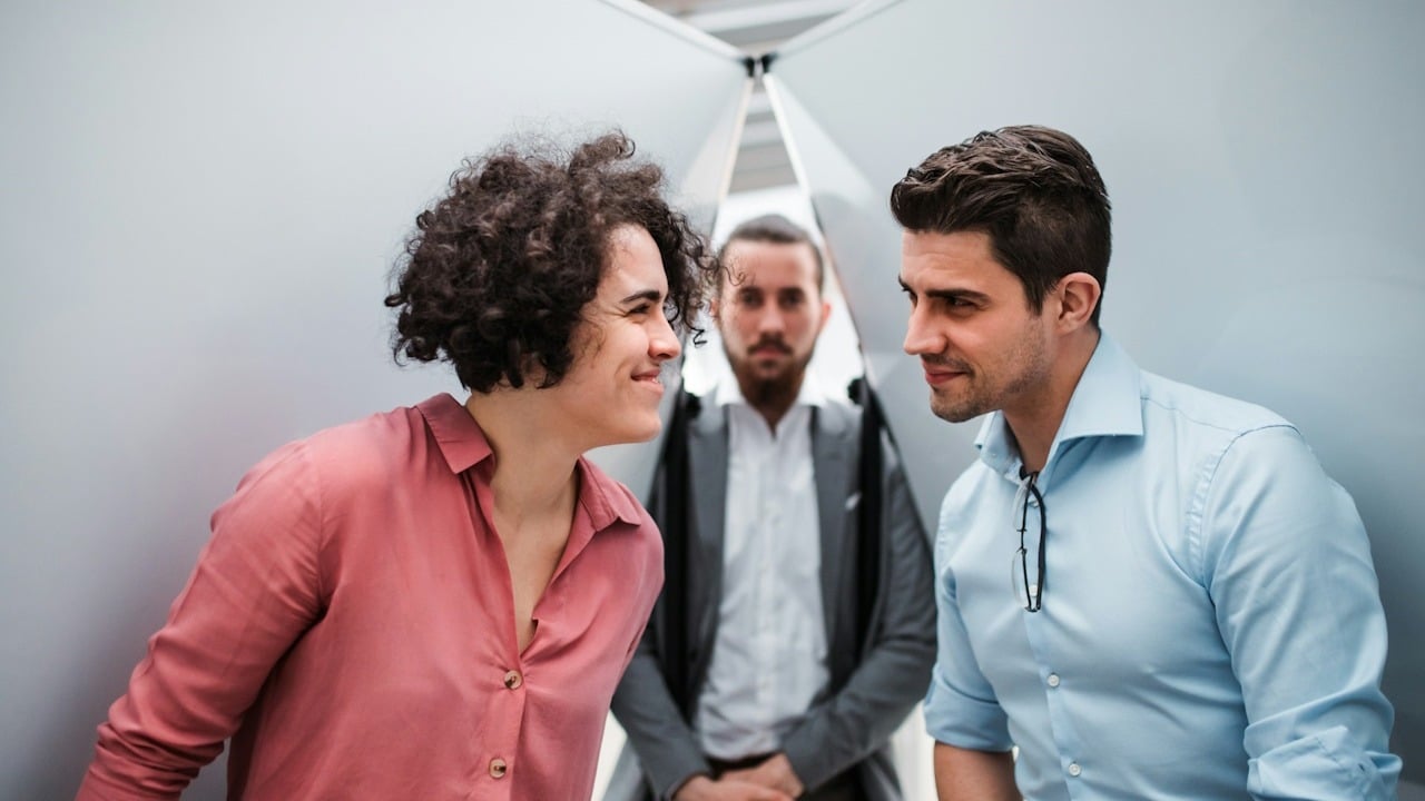 A couple smiling while a third person is looking at them.