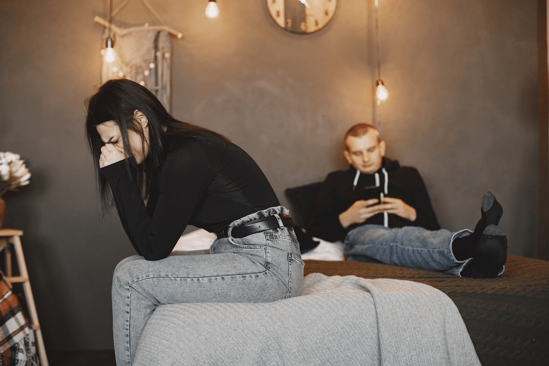 Photo of a Woman Crying while Sitting on a Bed