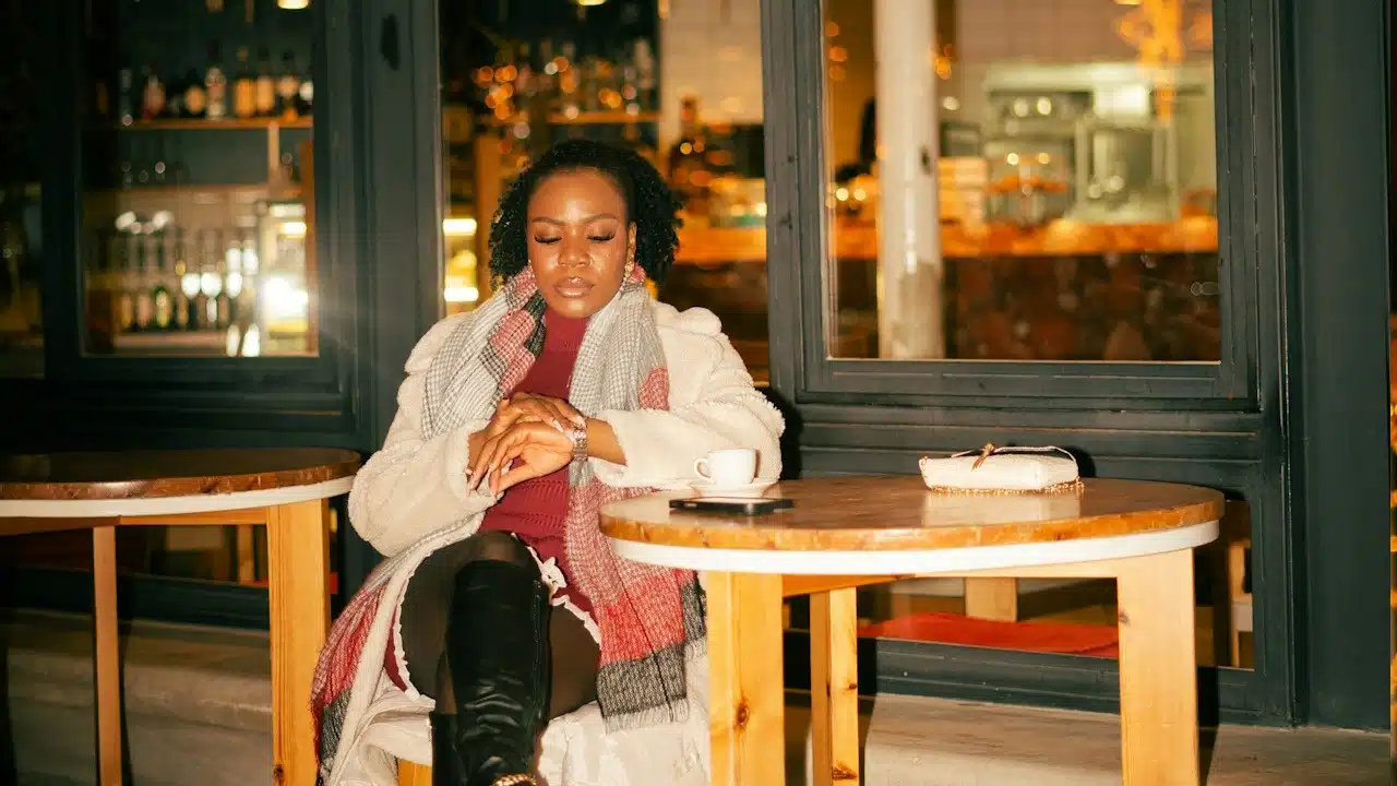 A woman sitting at a table while looking at her wristwatch.
