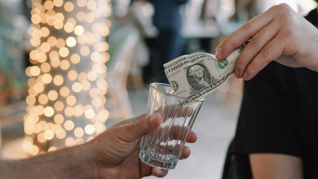 A person handing money to another person holding a glass.