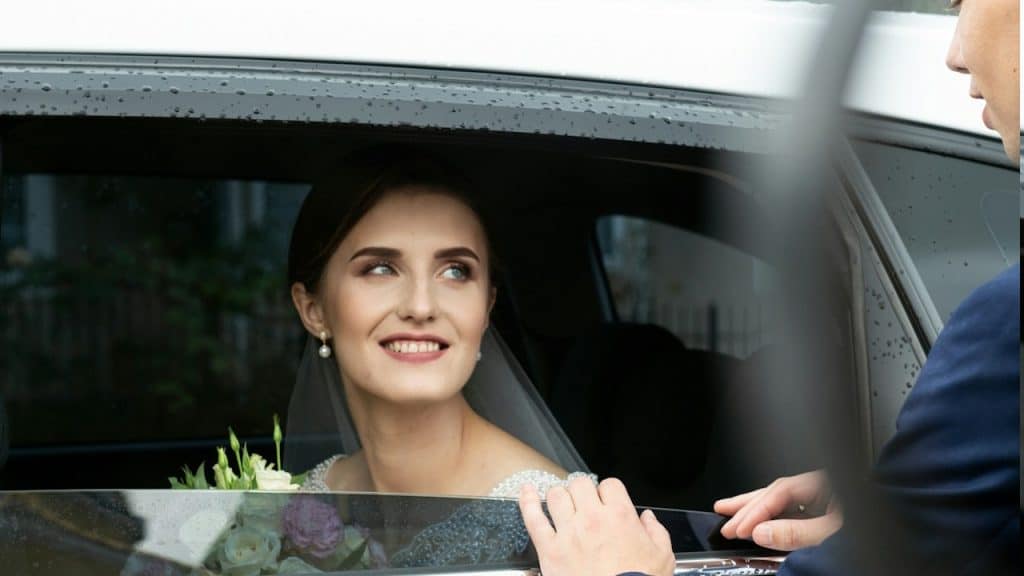 A woman sitting in a car with a bouquet of flowers.