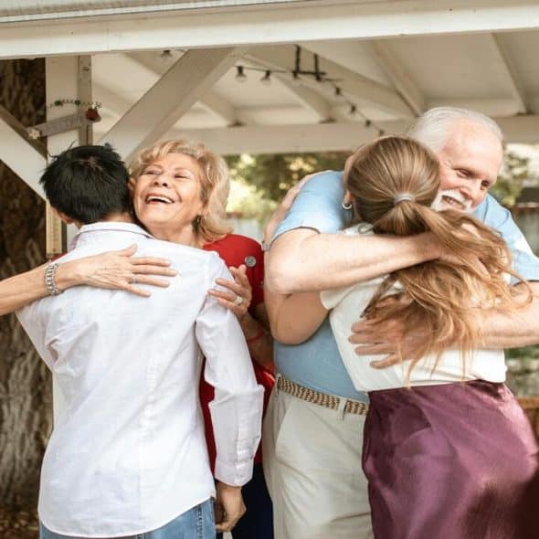 An elderly couple embracing their daughter and her boyfriend