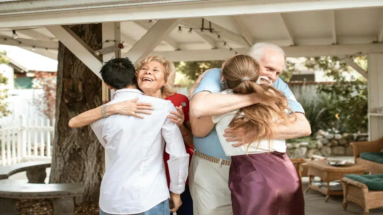 An elderly couple embracing their daughter and her boyfriend