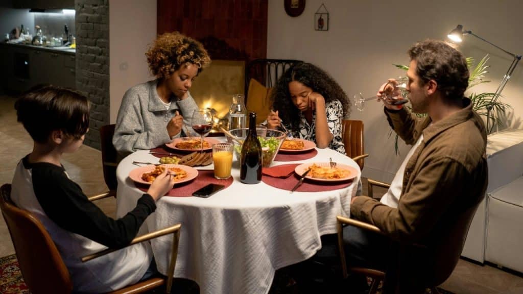 Four people sitting around a circular dining table eating a meal in a dimly lit room.