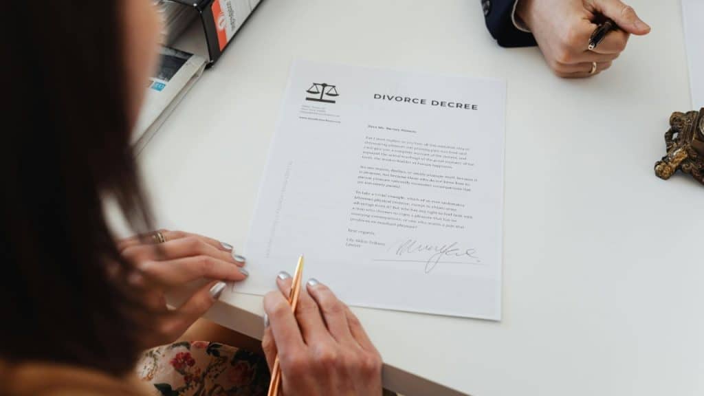 Overhead view of hands holding a pen over a document titled Divorce Decree on a desk.