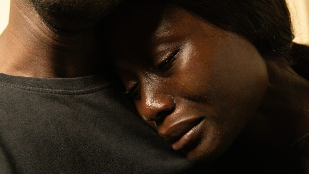 A close-up shot of a woman with her eyes closed resting her head on a man.