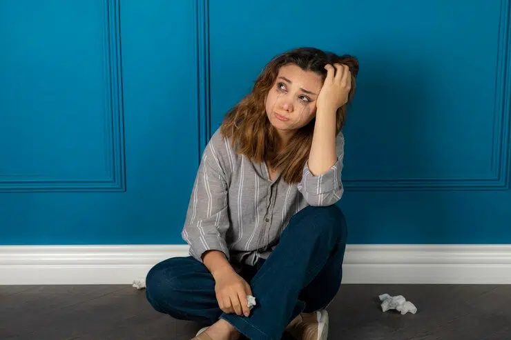 Depressed young woman sitting on the floor