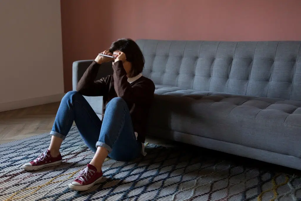 Full shot anxious woman sitting on floor