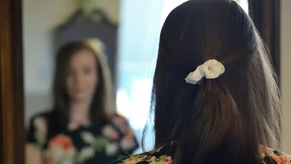 A woman looking at her reflection in the mirror.