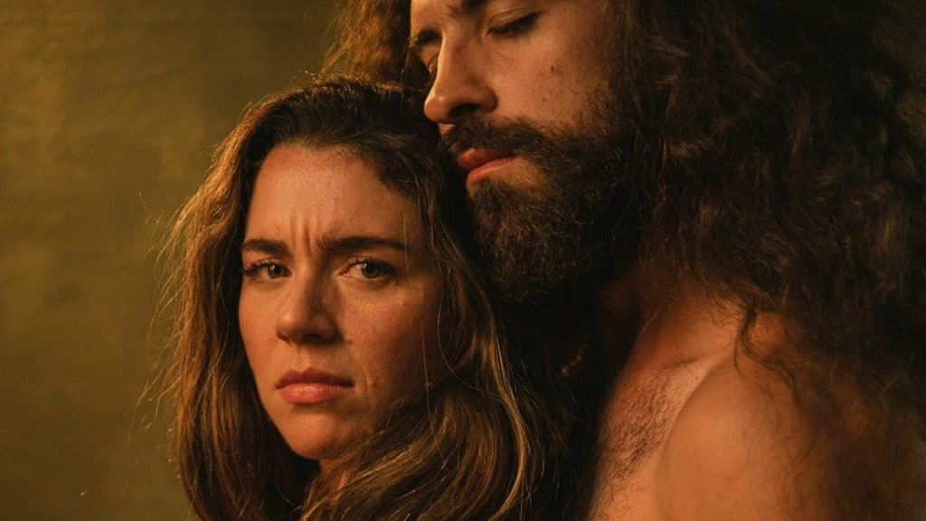 A man with long hair hugging a woman.