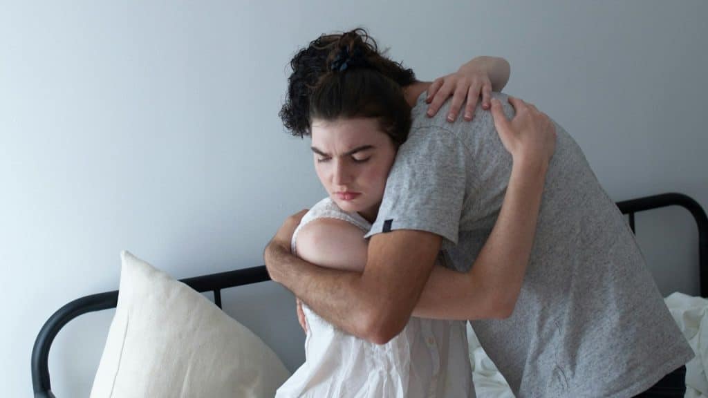 A man hugging a woman on top of a bed.