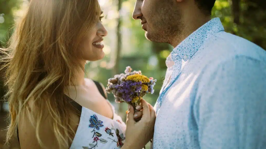 Man and woman facing each other while holding flowers.
