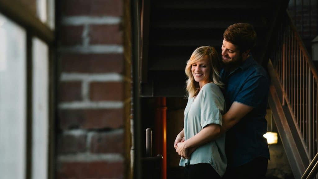 Man hugging woman from behind near stair.