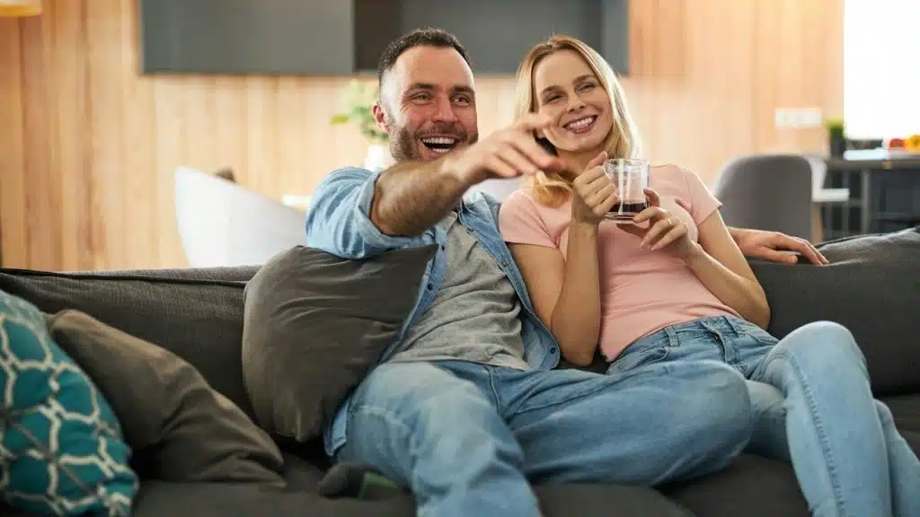 Charming woman holding a cup of coffee and smiling while her husband is pointing at something.