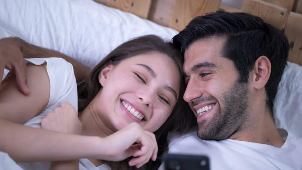 Young couple in a bed with mobile phones.