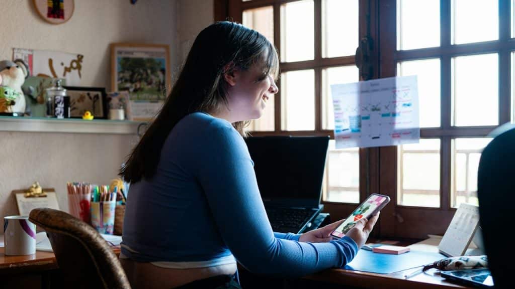 A woman sitting at a desk using a cell phone.