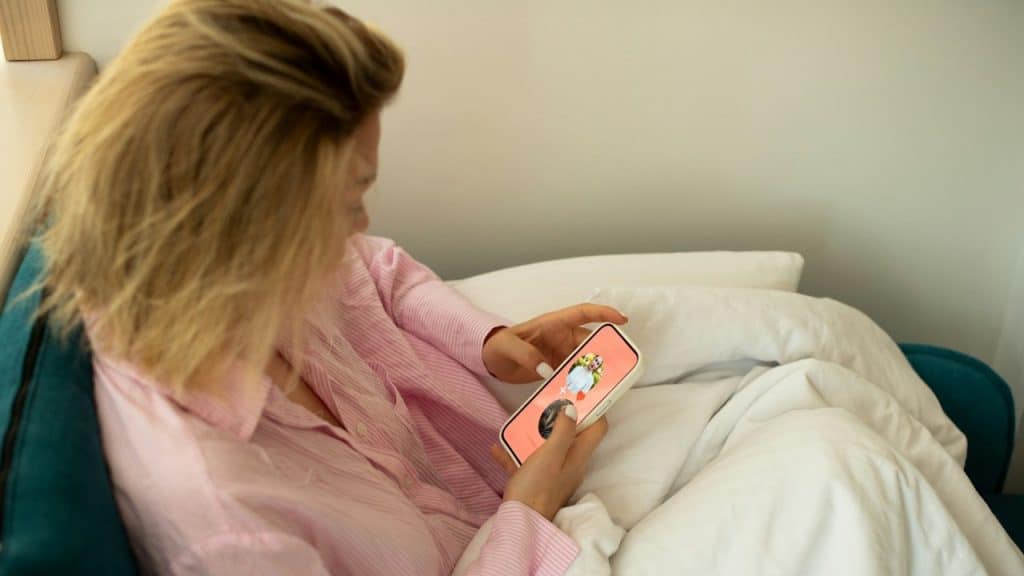 A woman holding a cellphone is using a dating app on it.