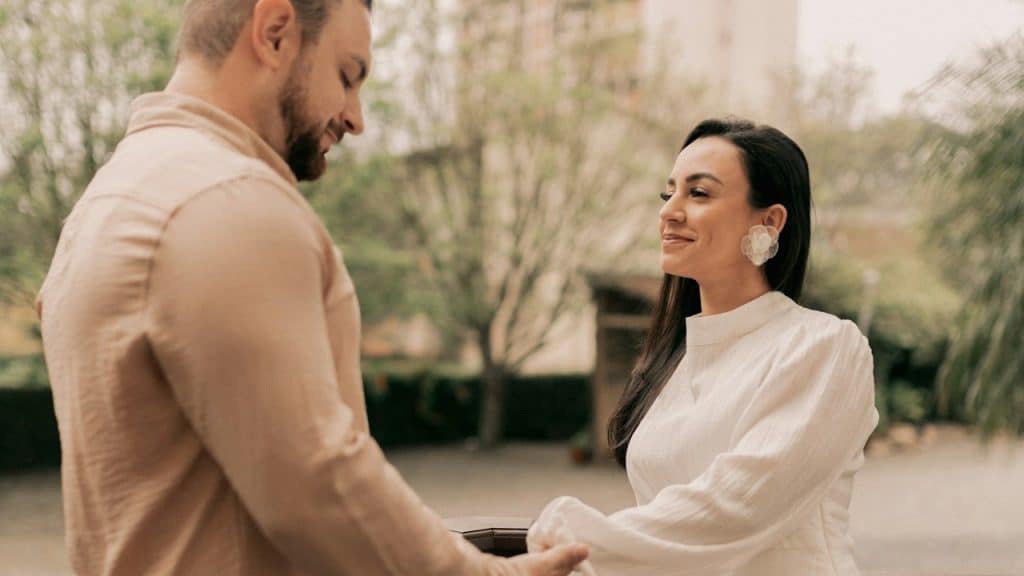 A couple holding hands while standing on a bridge.