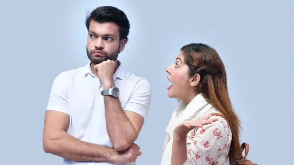 A woman with an open mouth gestures toward a man looking away from her.