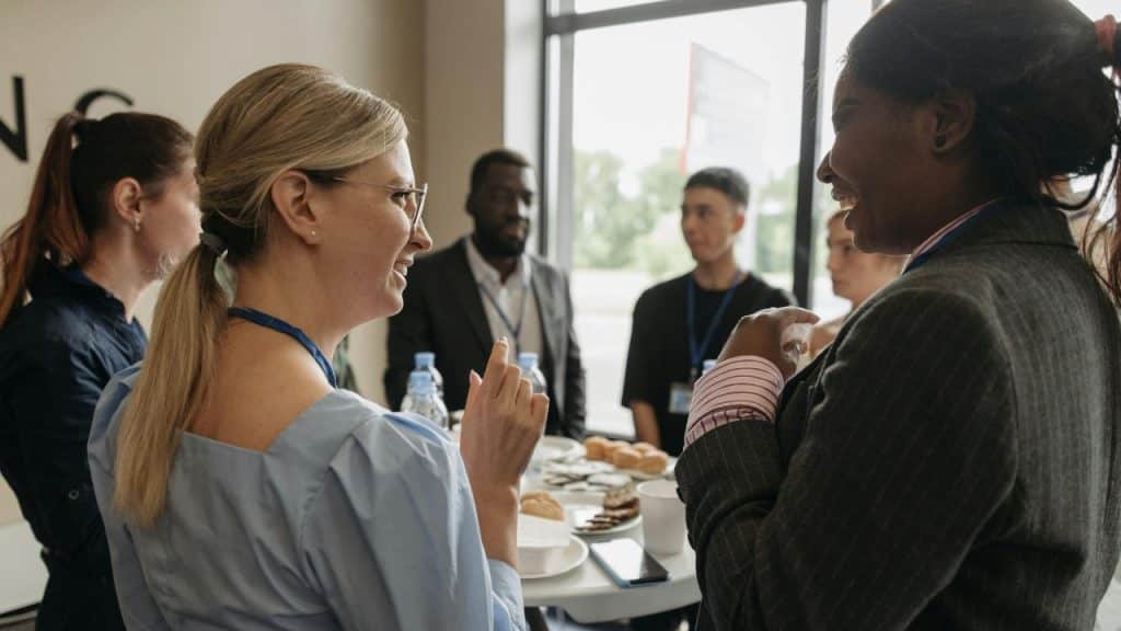 Several people stand around a table with snacks and drinks at an indoor networking event.