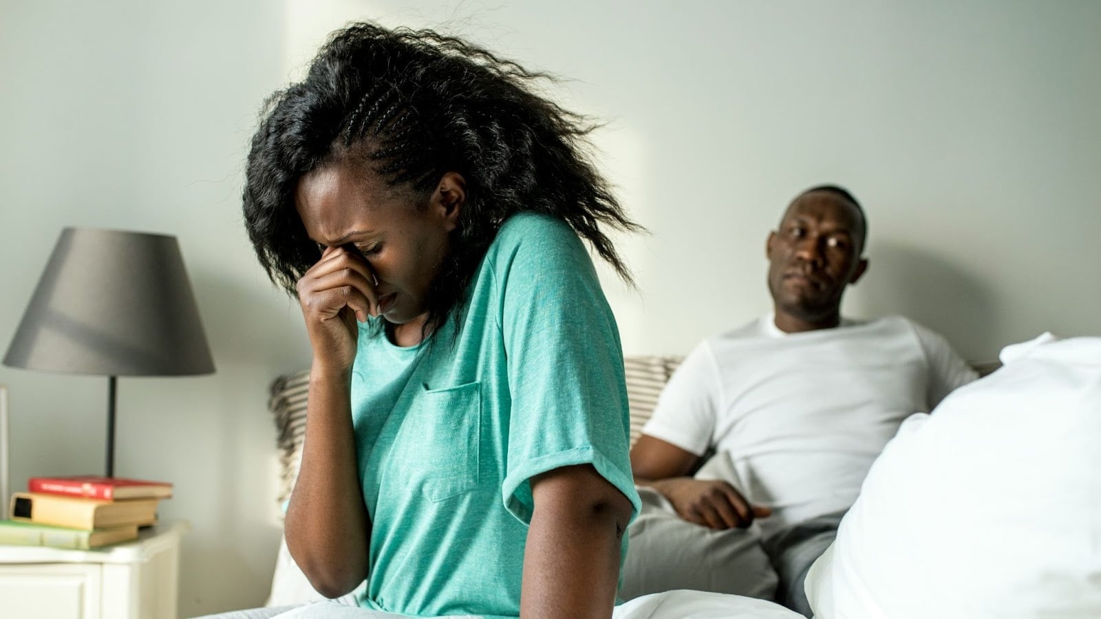 A woman crying and a man thinking behind her