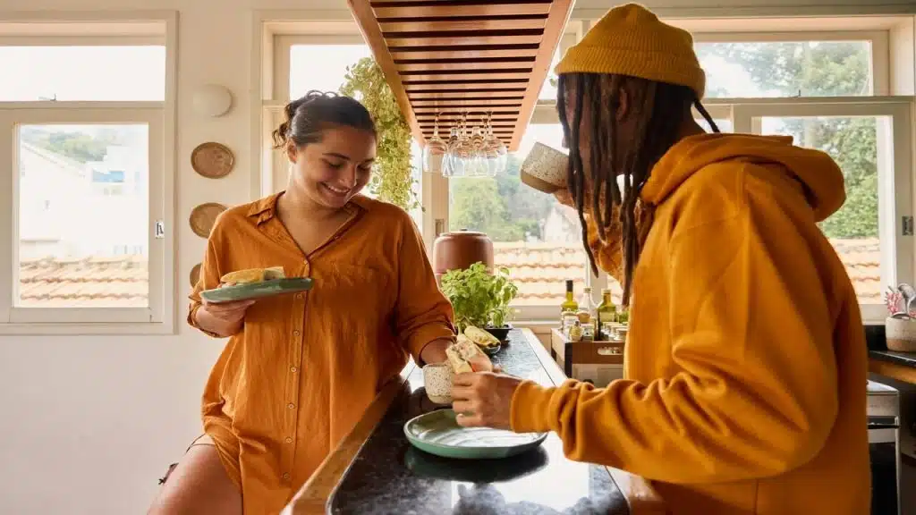 A couple laughing while preparing breakfast