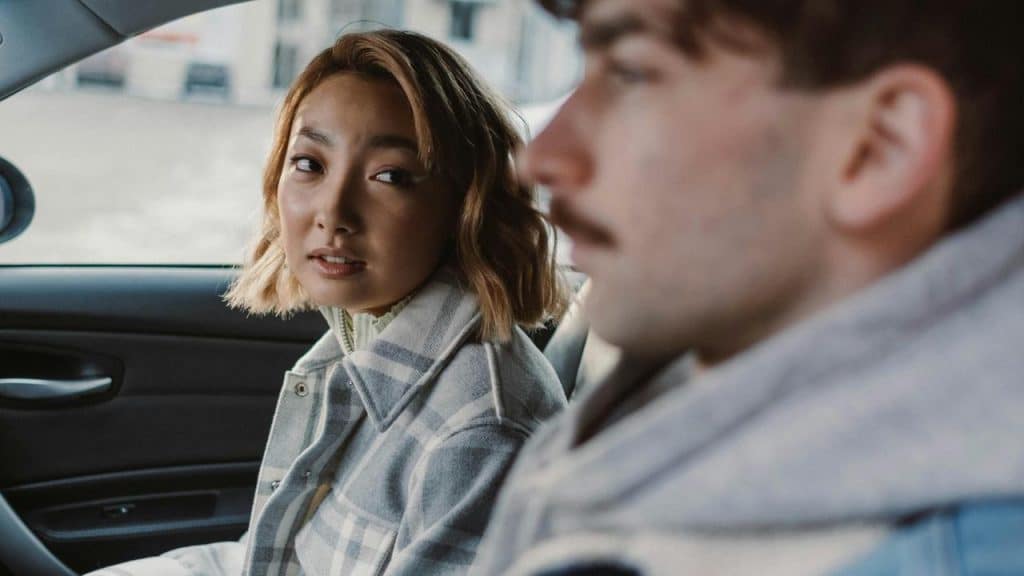 A woman looking at a man while sitting together in a car