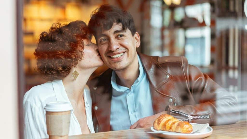 A woman kisses a smiling man on the cheek