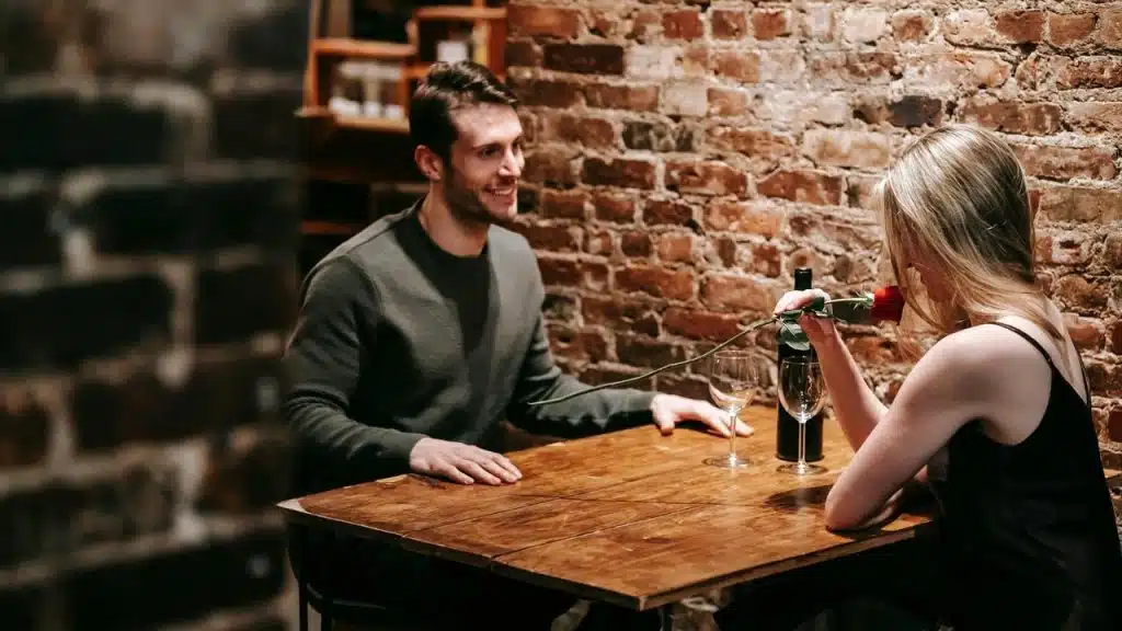 A couple sitting at a table in a restaurant, with the woman holding a red rose