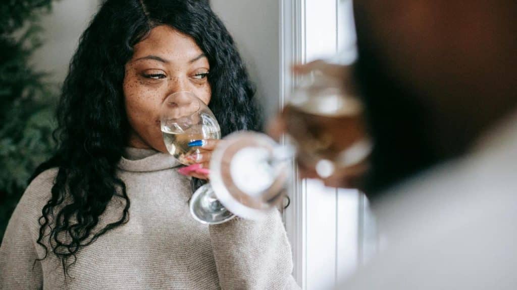 A woman sipping white wine by a window 
