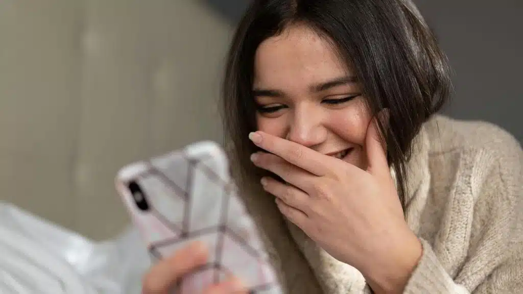 A woman smiles while looking at her phone