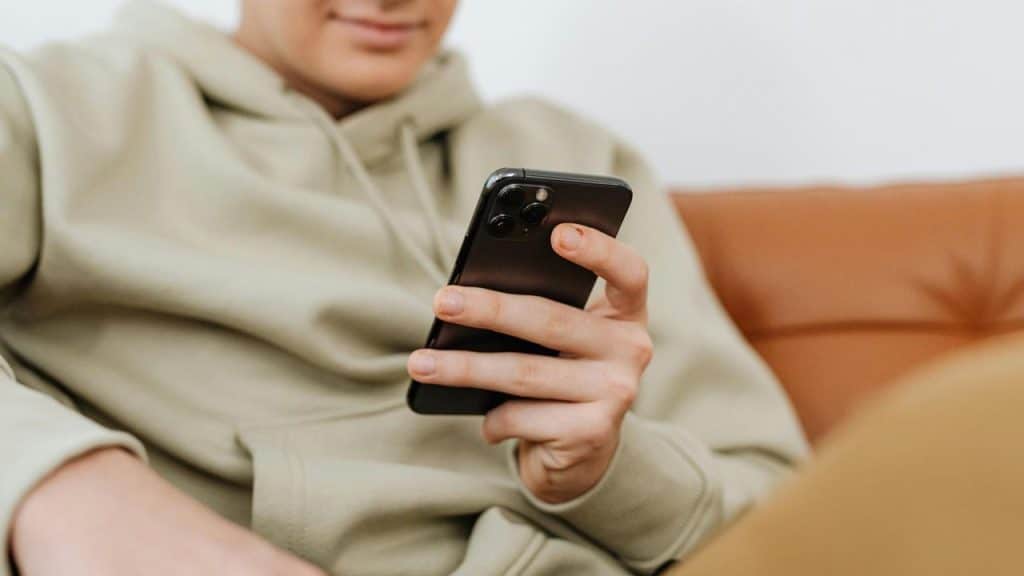A person sits on a couch using a smartphone