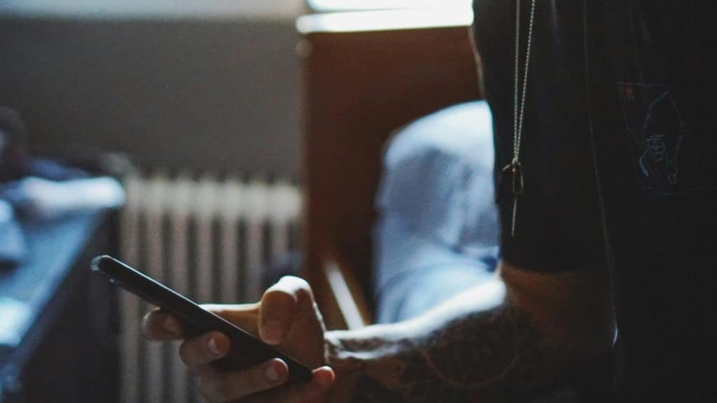 A person's hand holding a smartphone indoors.