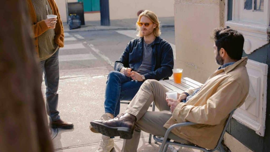 A group of people sitting outdoors with drinks and chatting casually.