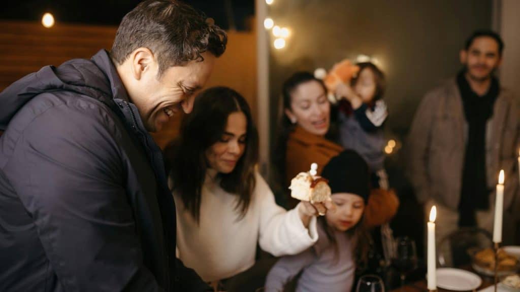 A group of people gathered around a table celebrating with cake and candlelight.