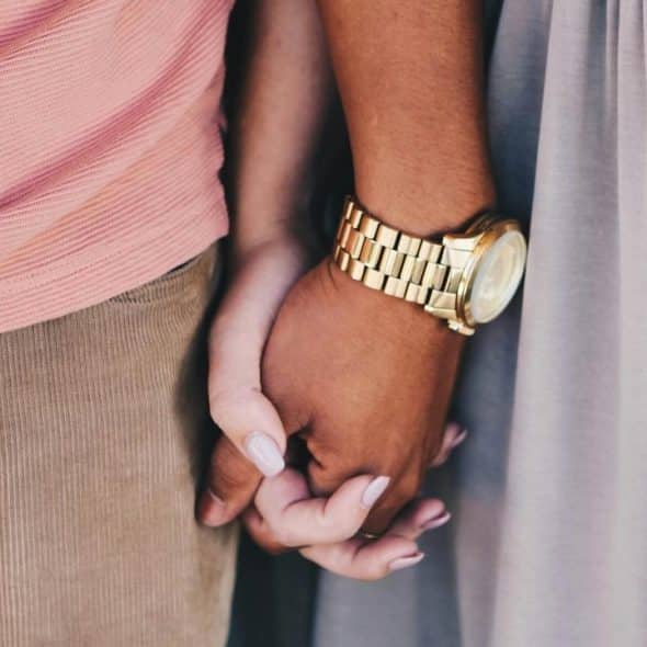 A close-up of two people holding hands, showing affection and connection.