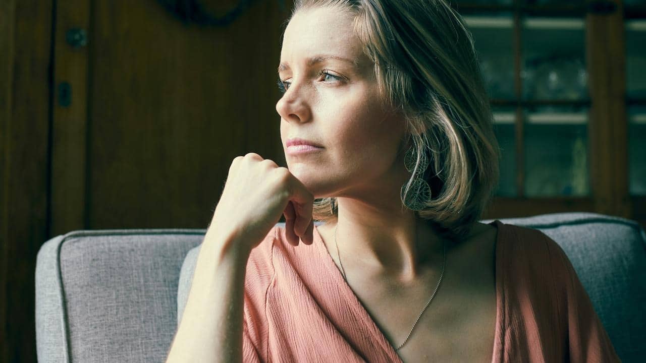 A woman gazes thoughtfully out a window