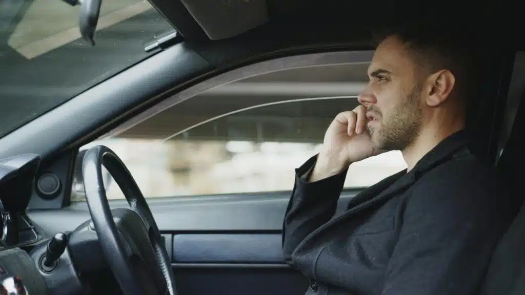 A man sitting in a car talking on a phone while driving.