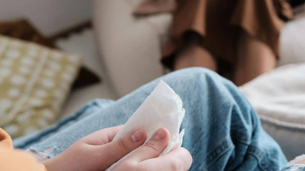 A person holding a tissue while sitting indoors.