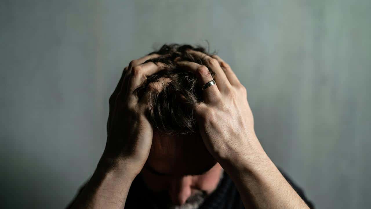 A man holds his head with both hands