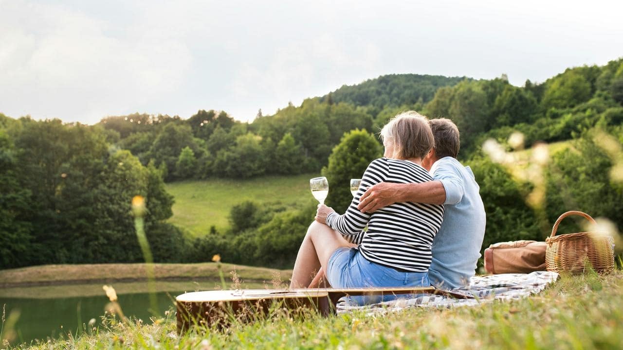 A couple sitting on a blanket and enjoying wine