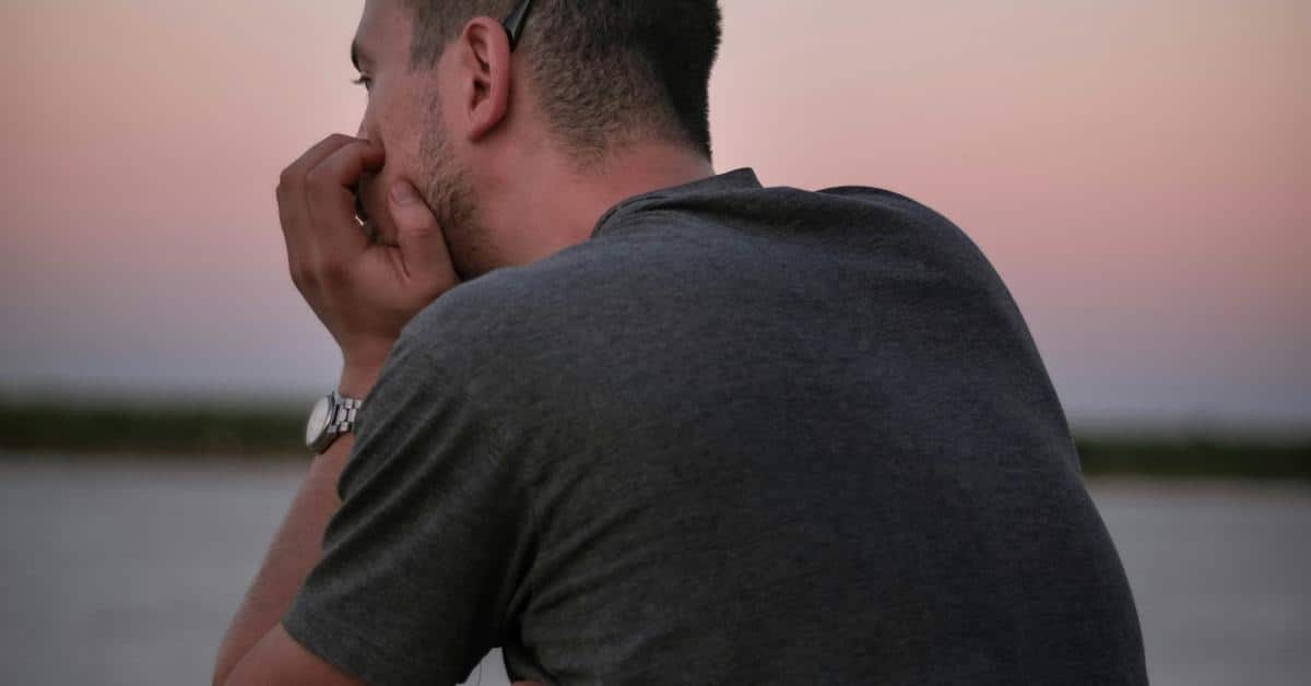 A man seen from behind, resting his chin on his hand