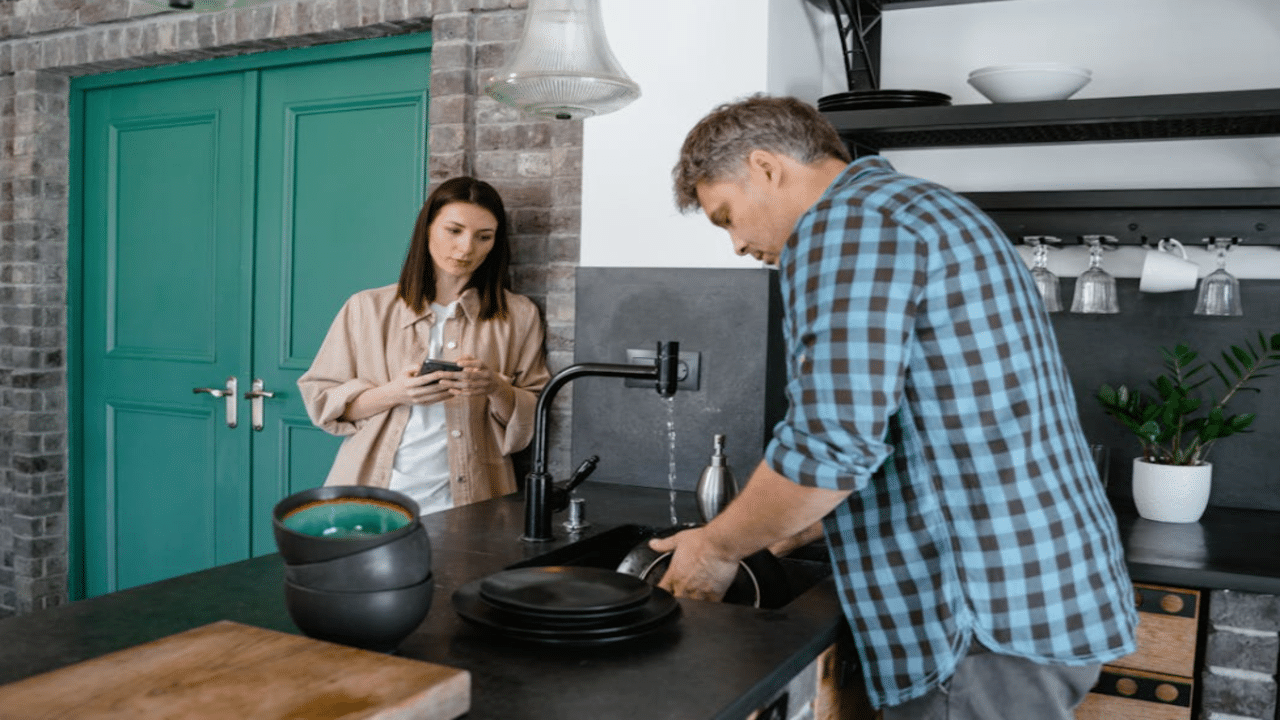 A woman watching her husband do the dishes